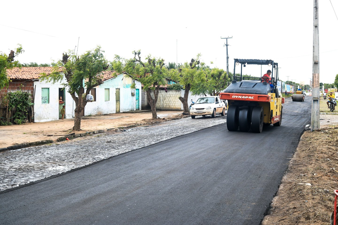 Construction worker smooths asphalt with a road roller.