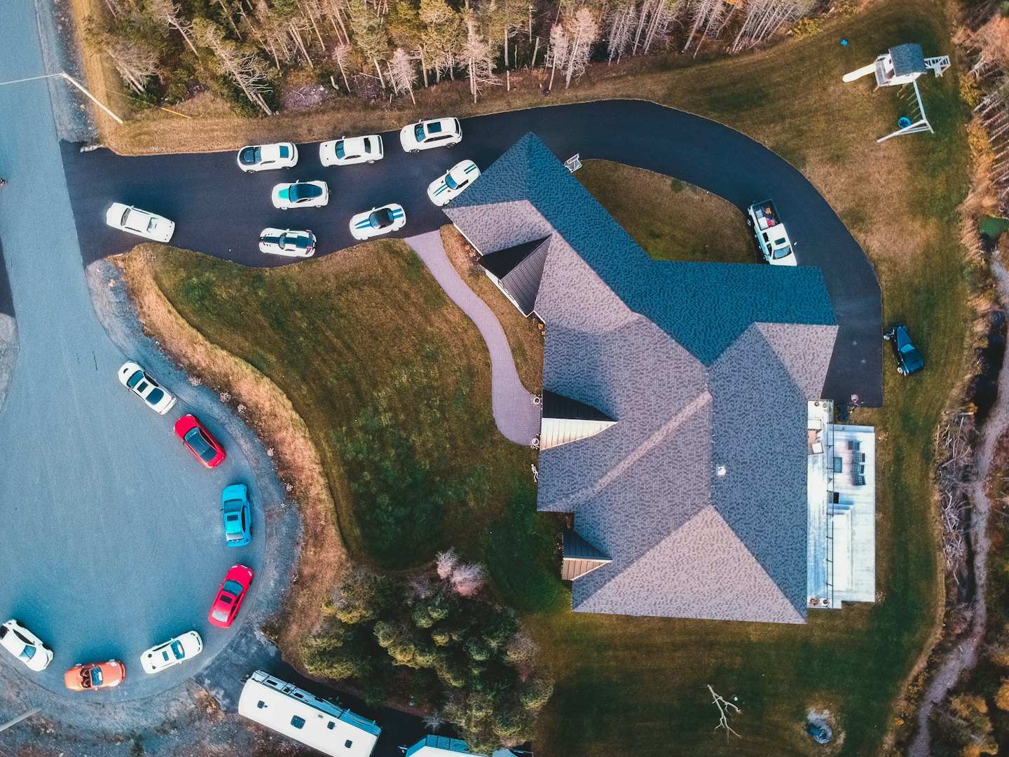 Aerial view of a large house with many cars gathered.