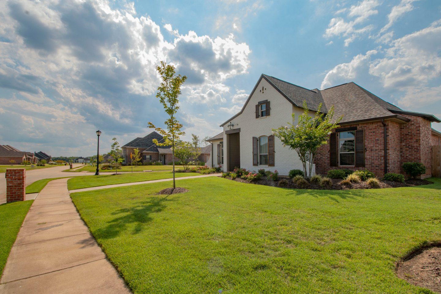 Modern suburban home with white brick and dark shutters on a sunny day.
