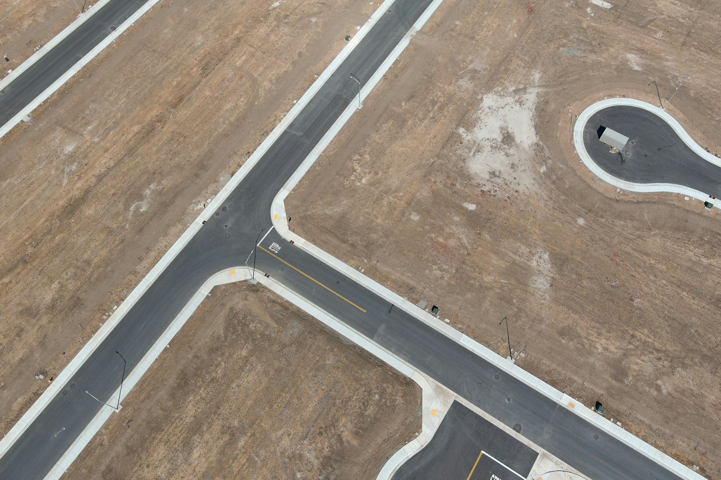 Aerial view of new housing development roads through bare earth.